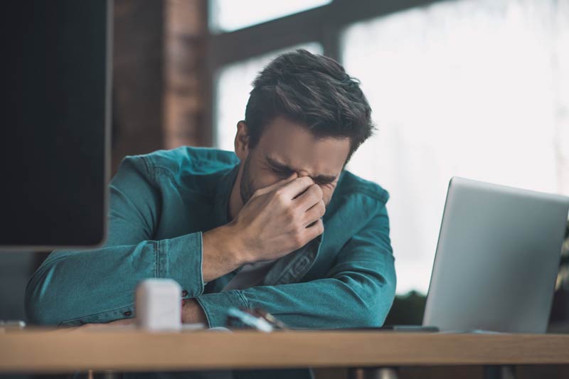 man with sinus pressure and allergies holding nose