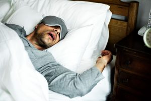 Man laying in bed on his back snoring