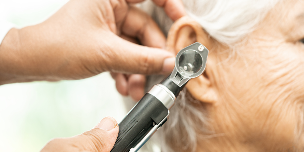 Doctor examining older woman's ear