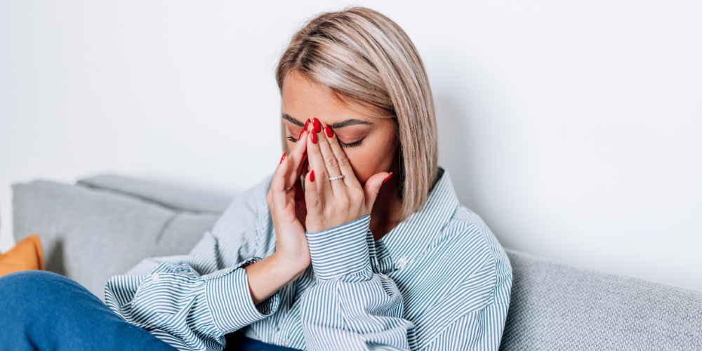 Woman holding hands to nose about to sneeze