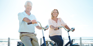 Older couple smiling while on bikes and enjoying their ENT health wellness
